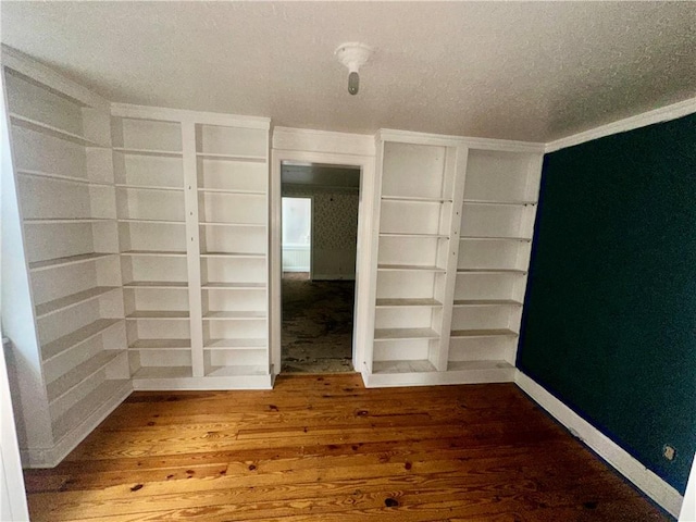 spare room featuring ornamental molding, wood-type flooring, and a textured ceiling