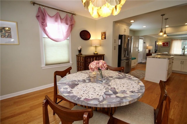 dining room with sink, a chandelier, and light hardwood / wood-style floors