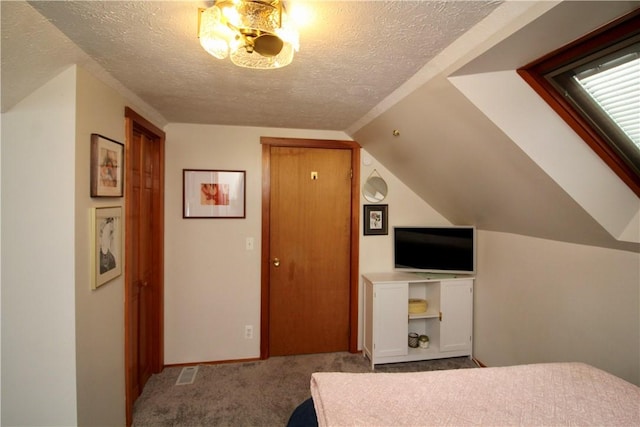 bedroom with lofted ceiling, carpet floors, and a textured ceiling