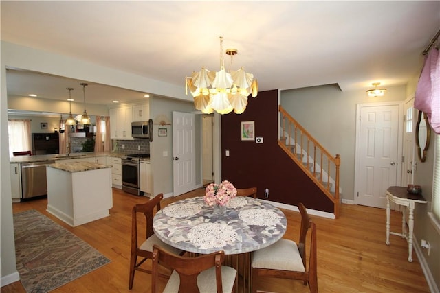 dining space featuring an inviting chandelier, sink, and light hardwood / wood-style floors