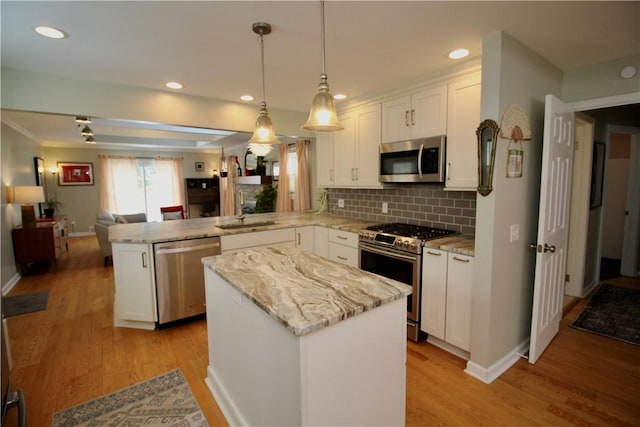 kitchen featuring a kitchen island, pendant lighting, white cabinetry, kitchen peninsula, and stainless steel appliances