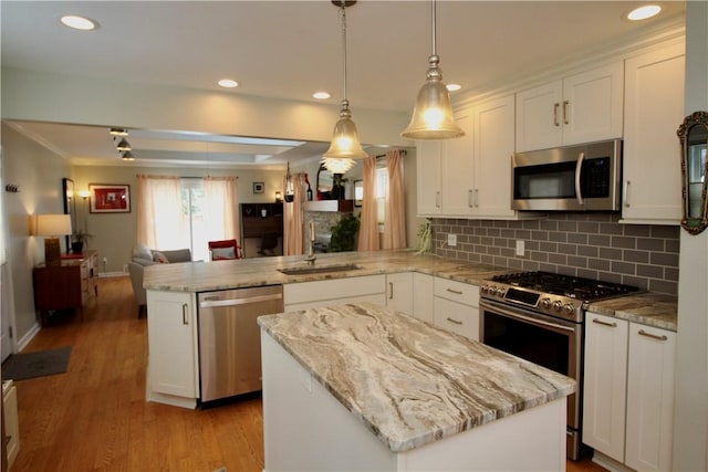 kitchen featuring appliances with stainless steel finishes, kitchen peninsula, a kitchen island, pendant lighting, and white cabinets