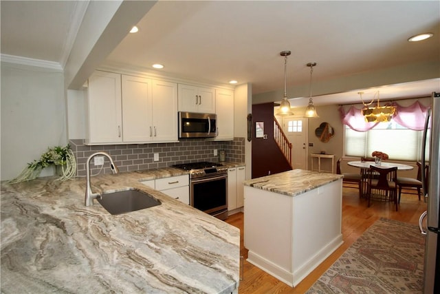 kitchen with sink, stainless steel appliances, light stone counters, white cabinets, and a kitchen island