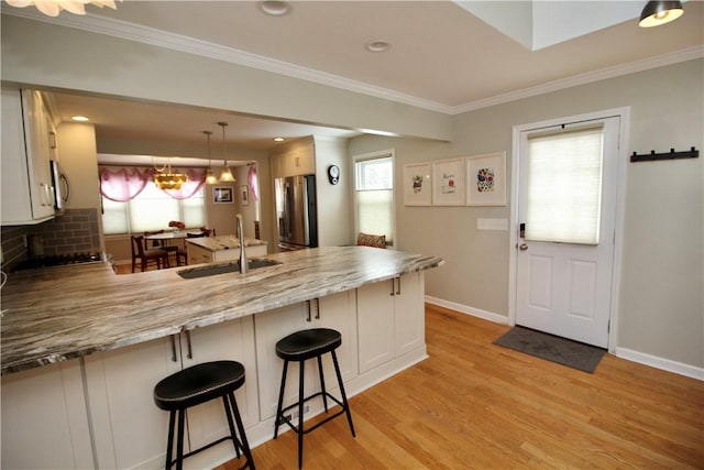 kitchen featuring sink, a breakfast bar area, white cabinetry, appliances with stainless steel finishes, and kitchen peninsula