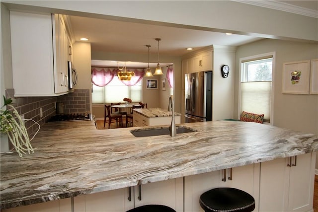 kitchen with sink, decorative light fixtures, kitchen peninsula, stainless steel appliances, and decorative backsplash