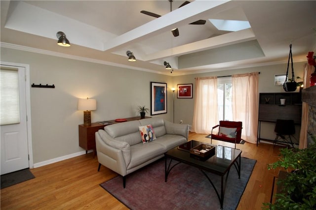 living room featuring light hardwood / wood-style floors, a raised ceiling, and ceiling fan