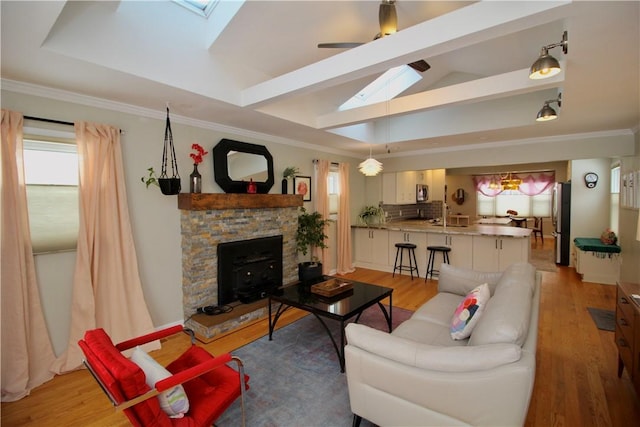 living room with ceiling fan, plenty of natural light, lofted ceiling with skylight, and light hardwood / wood-style floors