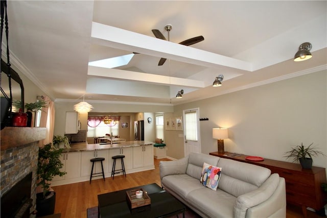 living room featuring beamed ceiling, ceiling fan, sink, and light wood-type flooring