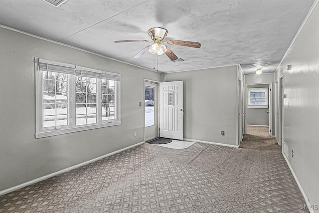 carpeted empty room featuring ceiling fan, plenty of natural light, and a textured ceiling