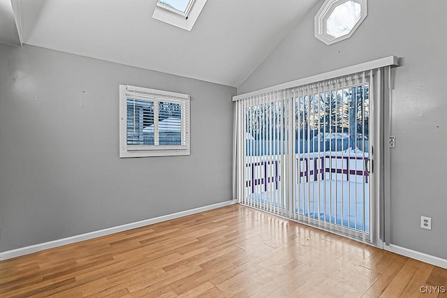 spare room featuring light hardwood / wood-style flooring and vaulted ceiling with skylight