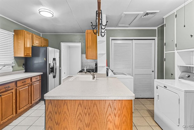 kitchen featuring washer / clothes dryer, stainless steel refrigerator with ice dispenser, a kitchen island with sink, and light tile patterned floors