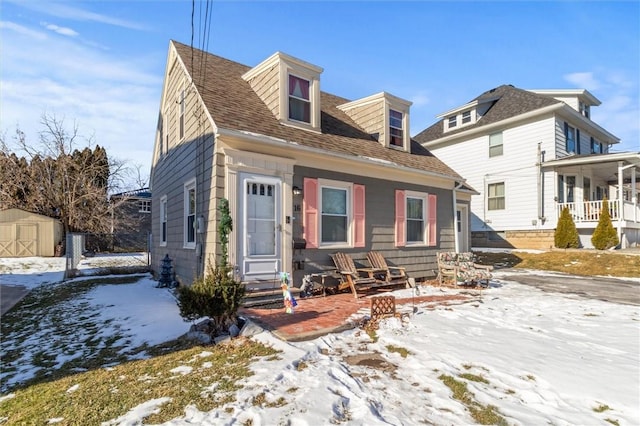 new england style home with a porch and a storage shed