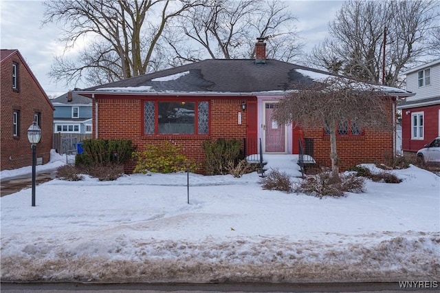 bungalow-style house featuring brick siding and a chimney