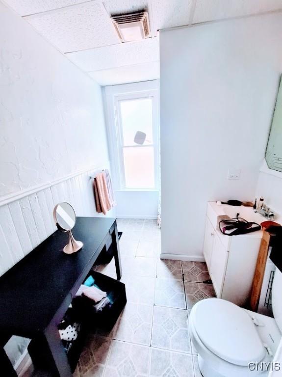 bathroom with a drop ceiling, tile patterned floors, and toilet