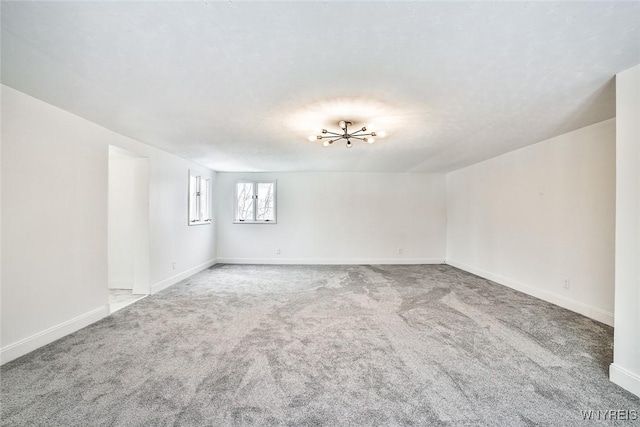 carpeted empty room with a notable chandelier