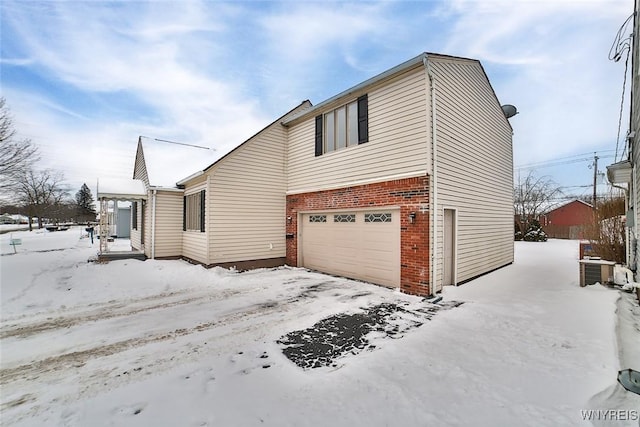 snow covered property featuring a garage and cooling unit