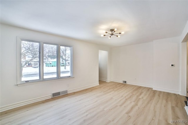 empty room with a chandelier and light hardwood / wood-style flooring