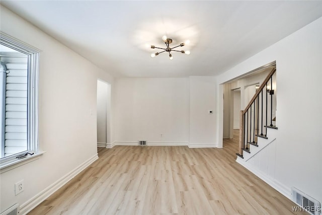 unfurnished room featuring a chandelier and light hardwood / wood-style floors