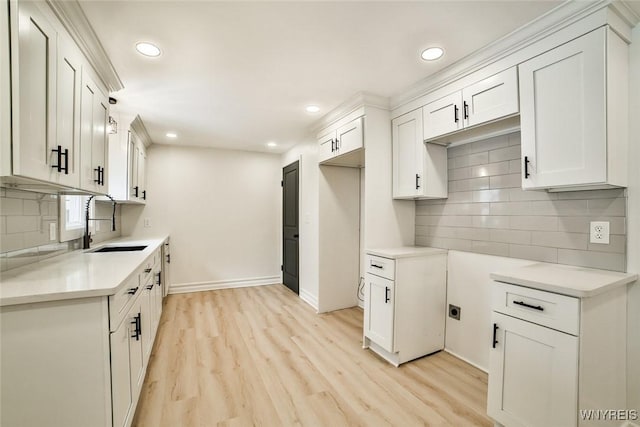 kitchen featuring tasteful backsplash, light hardwood / wood-style floors, sink, and white cabinets