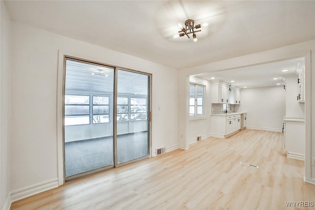 unfurnished living room with sink and light hardwood / wood-style floors