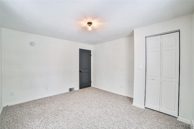 unfurnished bedroom featuring light carpet and a closet