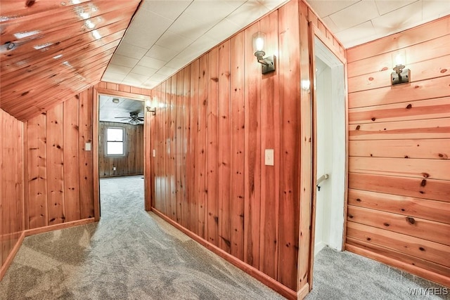 additional living space with carpet flooring, vaulted ceiling, and wood walls