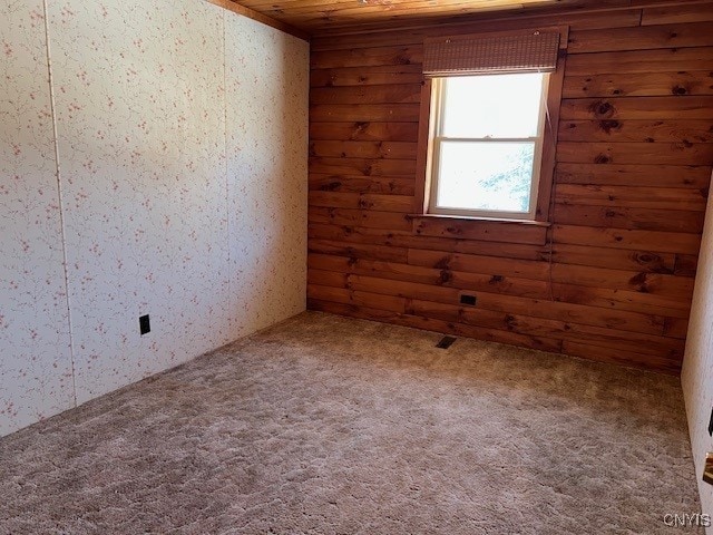 empty room featuring log walls, carpet floors, and wooden ceiling