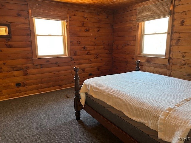 bedroom featuring wood ceiling, log walls, and carpet flooring