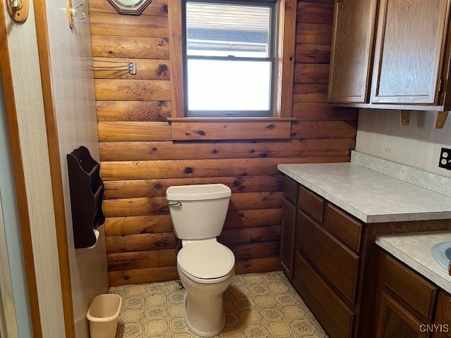 bathroom featuring vanity, toilet, and rustic walls