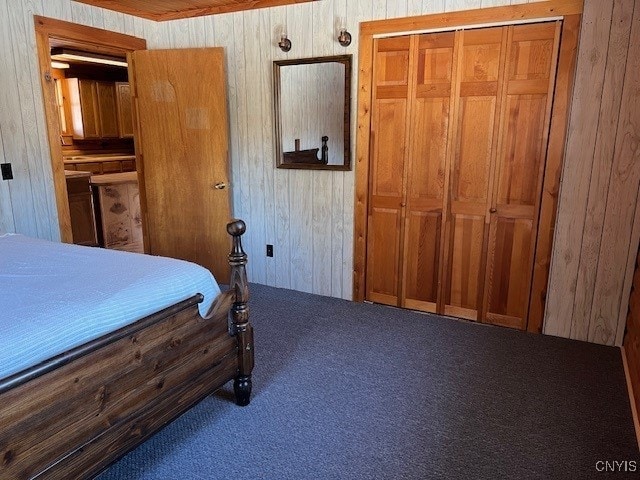 carpeted bedroom featuring wooden ceiling, wooden walls, and a closet