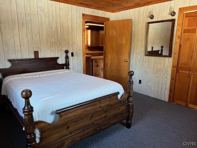 carpeted bedroom featuring ensuite bath, wooden walls, and wooden ceiling