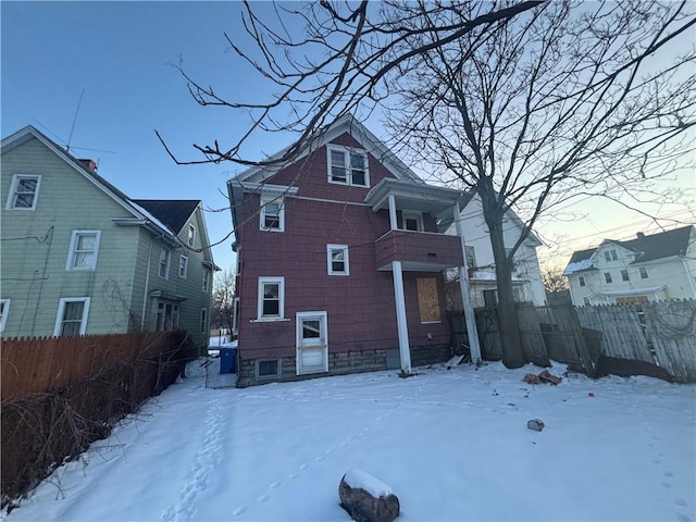 snow covered rear of property with a balcony