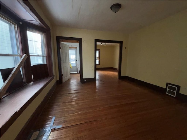 unfurnished room with dark wood-type flooring and plenty of natural light