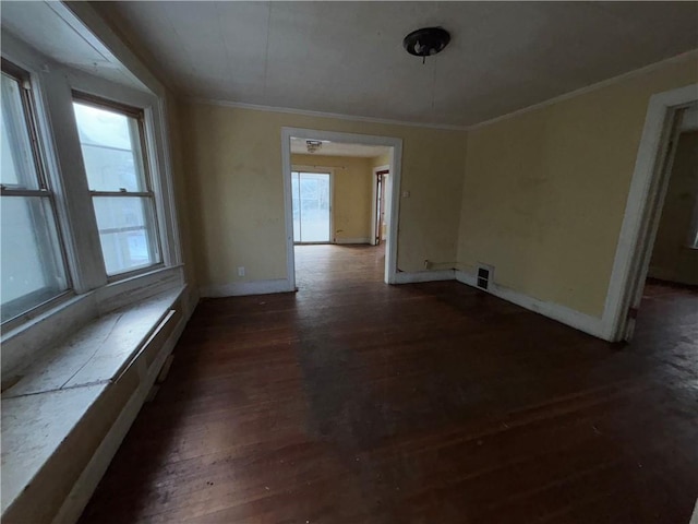 empty room featuring dark wood-type flooring and ornamental molding