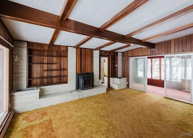 unfurnished living room with wood walls, carpet, beam ceiling, and built in features