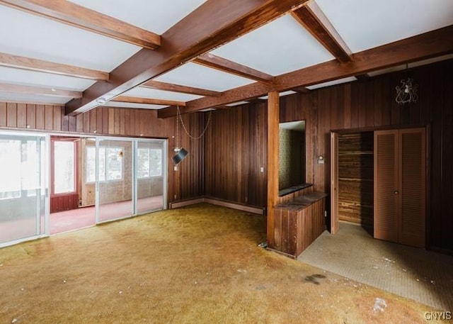 spare room featuring wood walls and beamed ceiling