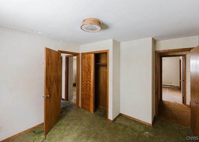 unfurnished bedroom with a baseboard radiator, a closet, dark carpet, and baseboards