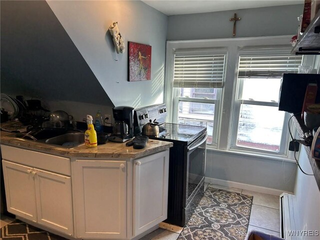 kitchen with white cabinetry, sink, light tile patterned floors, light stone counters, and electric stove