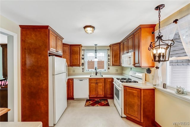 kitchen with pendant lighting, sink, white appliances, and a notable chandelier