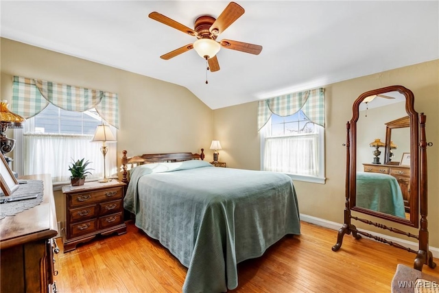 bedroom with ceiling fan, vaulted ceiling, multiple windows, and light wood-type flooring