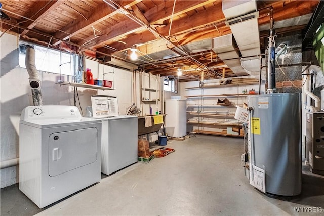 basement with white refrigerator, gas water heater, and separate washer and dryer