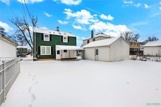 snow covered rear of property featuring an outdoor structure