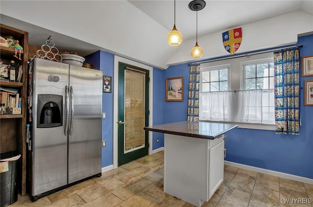 kitchen with a kitchen island, decorative light fixtures, lofted ceiling, white cabinets, and stainless steel fridge