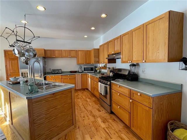 kitchen featuring lofted ceiling, sink, a center island with sink, light wood-type flooring, and appliances with stainless steel finishes