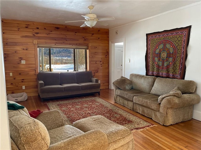 living room featuring hardwood / wood-style flooring, ceiling fan, ornamental molding, and wooden walls