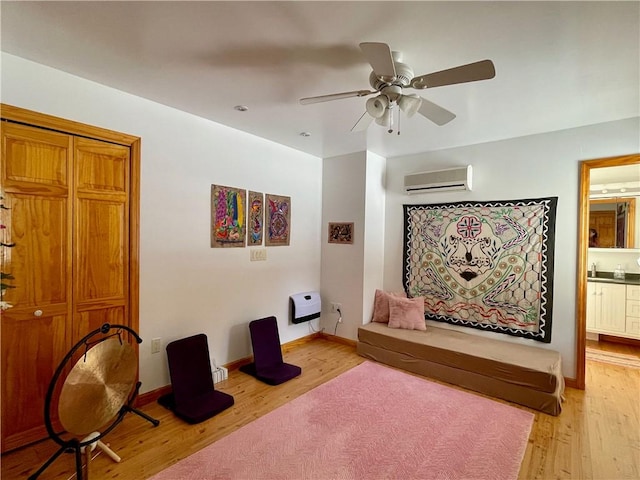 sitting room featuring a wall mounted air conditioner, light hardwood / wood-style flooring, and ceiling fan