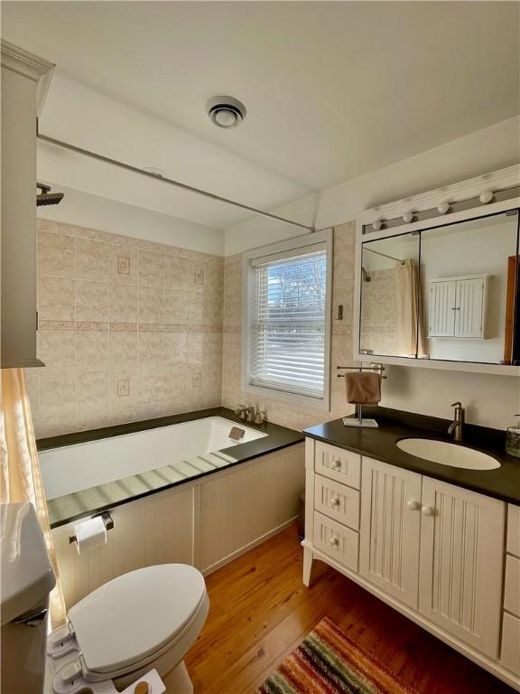 full bathroom featuring hardwood / wood-style flooring, vanity, washtub / shower combination, and toilet