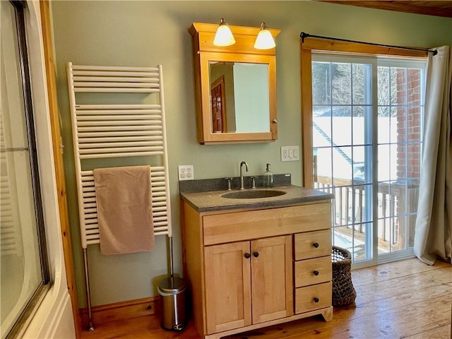 bathroom with vanity, hardwood / wood-style floors, radiator heating unit, and enclosed tub / shower combo