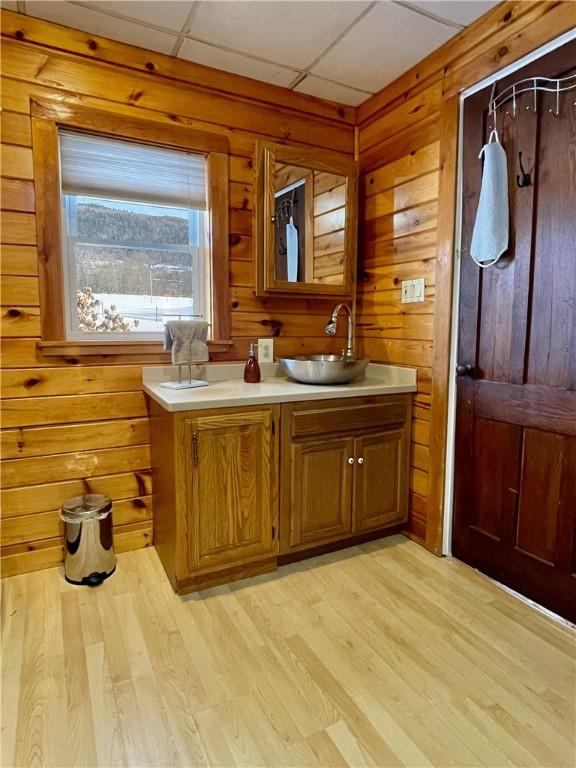 bathroom with vanity, hardwood / wood-style flooring, a paneled ceiling, and wood walls