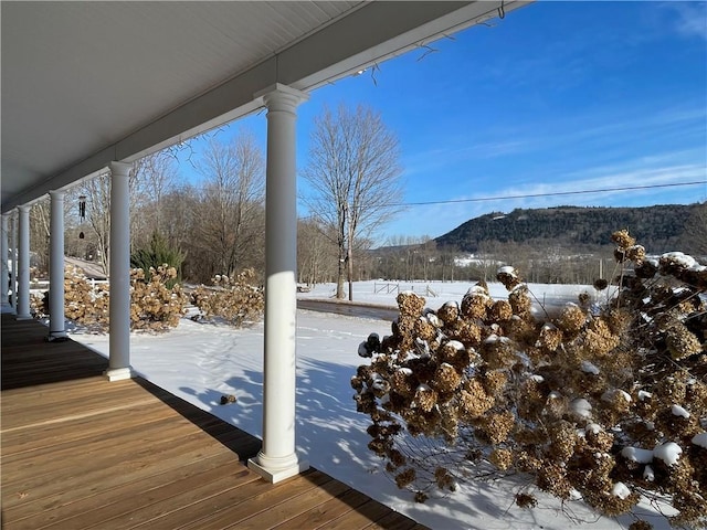 snow covered deck with a porch and a mountain view